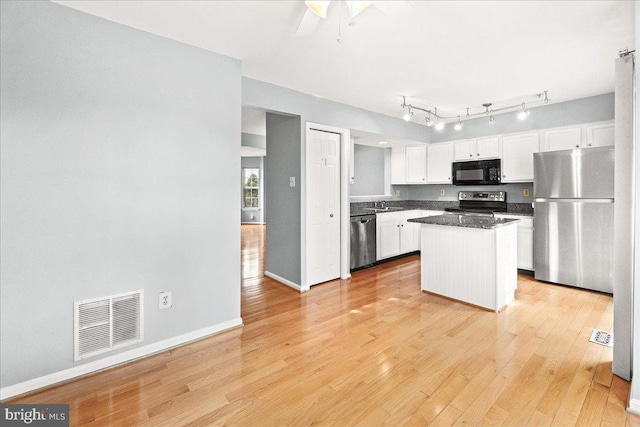 kitchen with dark countertops, visible vents, appliances with stainless steel finishes, white cabinets, and a kitchen island