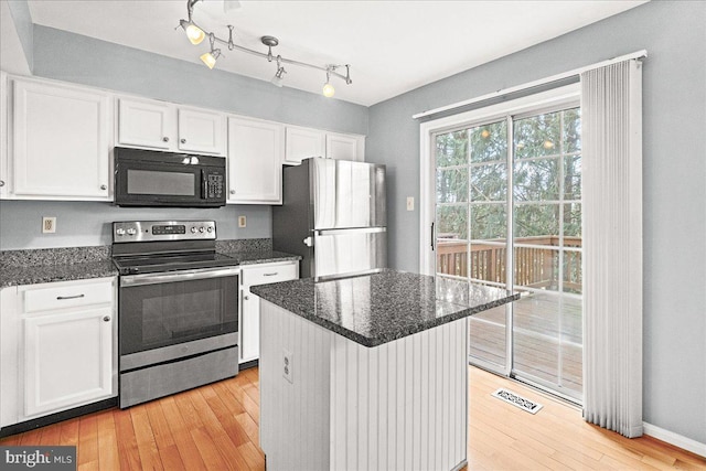 kitchen featuring dark stone counters, appliances with stainless steel finishes, light wood-style flooring, and white cabinets