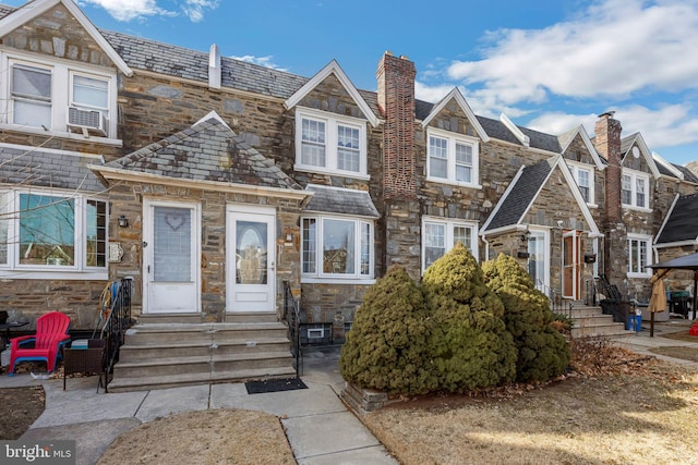 view of front of house with entry steps, a residential view, a high end roof, and stone siding