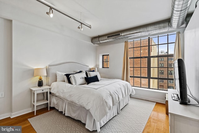 bedroom with baseboards, multiple windows, and light wood finished floors