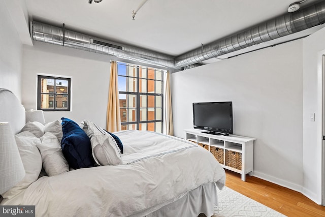 bedroom with visible vents, baseboards, and wood finished floors