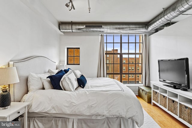 bedroom with light wood-style flooring, visible vents, and track lighting