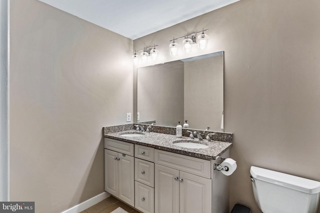 bathroom with tile patterned floors, a sink, toilet, and double vanity