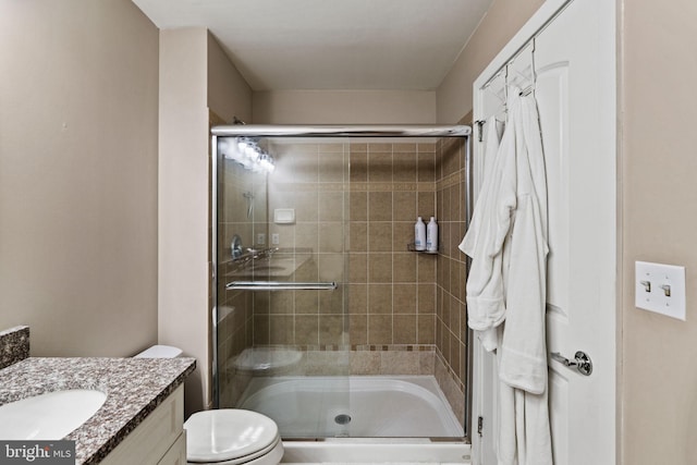 bathroom with toilet, a stall shower, and vanity