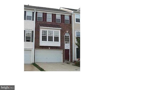 view of property with driveway, a garage, and brick siding