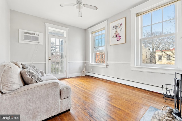 living area featuring hardwood / wood-style floors, an AC wall unit, ceiling fan, and a baseboard radiator