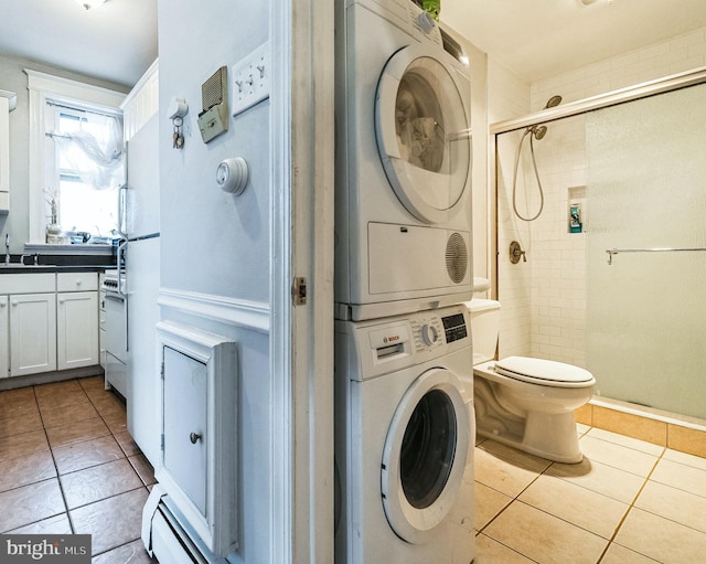 laundry area featuring a sink, laundry area, tile patterned floors, and stacked washing maching and dryer