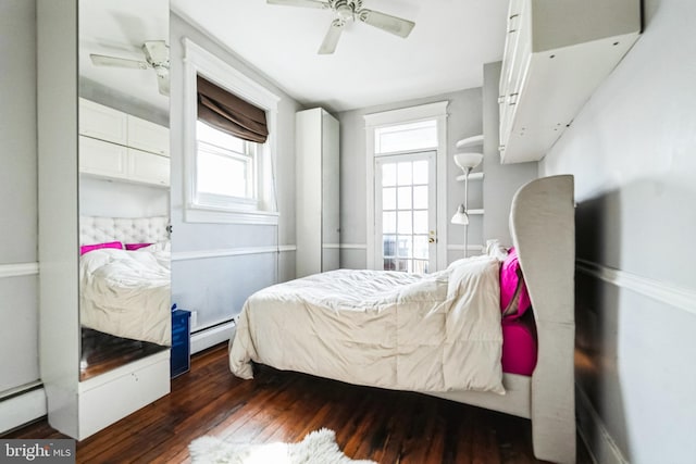 bedroom featuring baseboard heating, multiple windows, a baseboard heating unit, and wood-type flooring