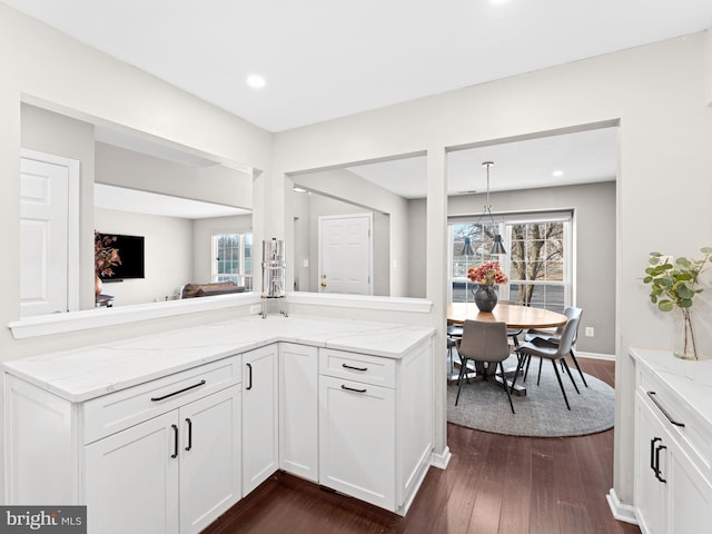 kitchen with dark wood-style floors, white cabinetry, pendant lighting, and light stone counters