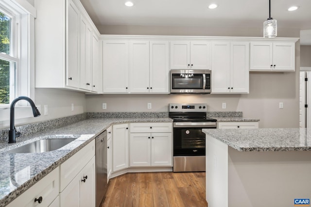 kitchen featuring decorative light fixtures, sink, stainless steel appliances, and white cabinetry