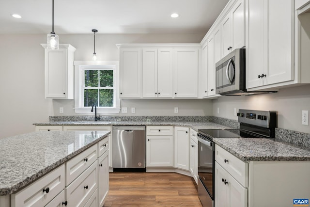 kitchen featuring hardwood / wood-style floors, sink, appliances with stainless steel finishes, white cabinets, and pendant lighting