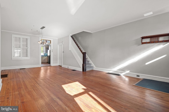 unfurnished living room with hardwood / wood-style floors, a chandelier, and crown molding