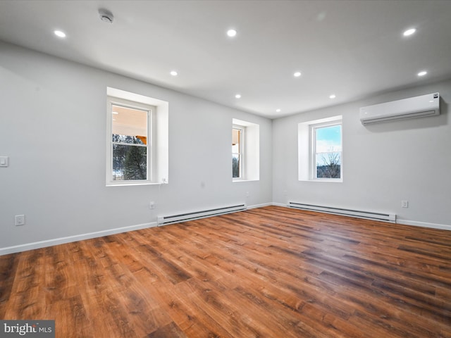 spare room with hardwood / wood-style floors, a wall mounted air conditioner, and baseboard heating