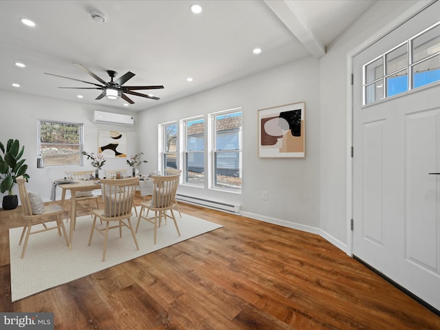 dining room featuring baseboard heating, a wall mounted AC, a wealth of natural light, and hardwood / wood-style floors