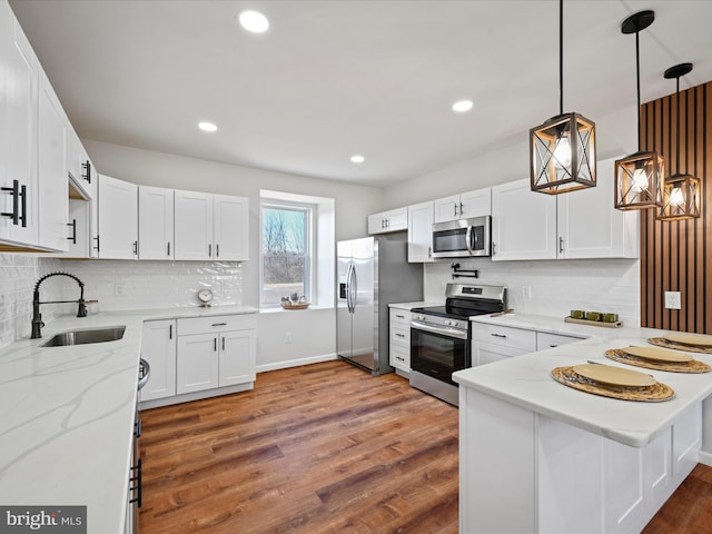 kitchen with white cabinetry, stainless steel appliances, dark wood-type flooring, kitchen peninsula, and hanging light fixtures