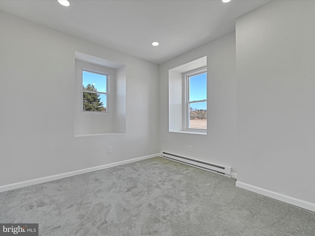 carpeted spare room with baseboard heating and a wealth of natural light