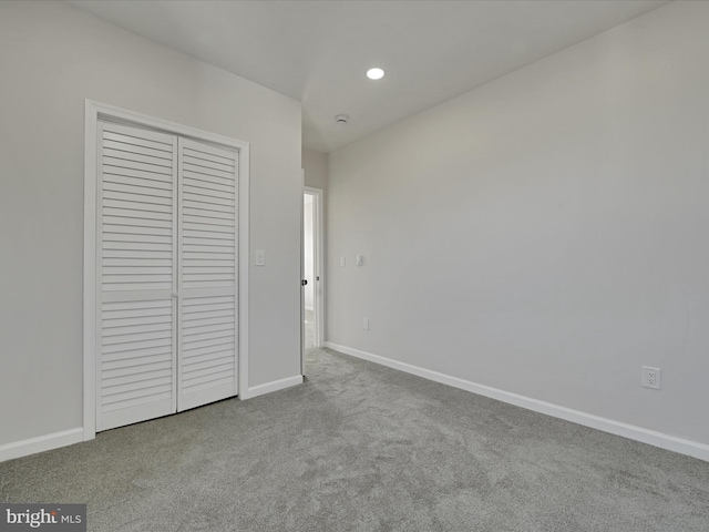 unfurnished bedroom featuring a closet and light colored carpet