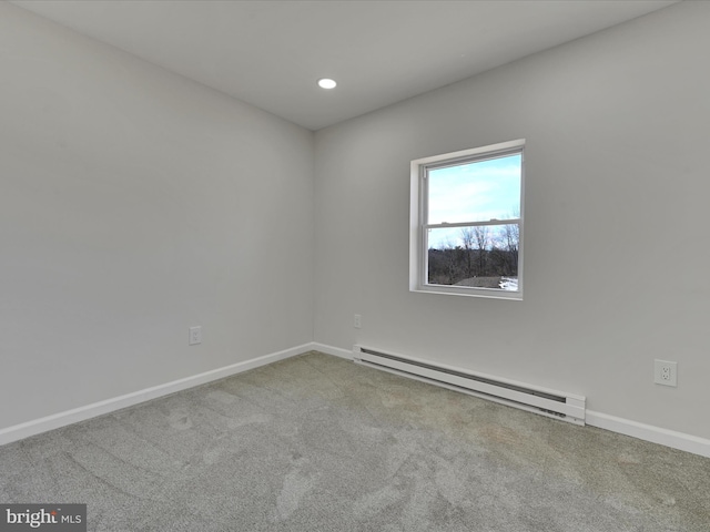 carpeted spare room featuring a baseboard heating unit