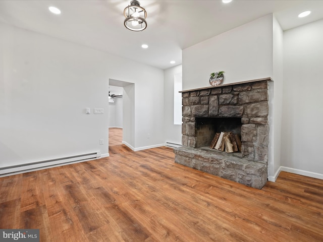 unfurnished living room with a fireplace, a baseboard heating unit, and hardwood / wood-style floors