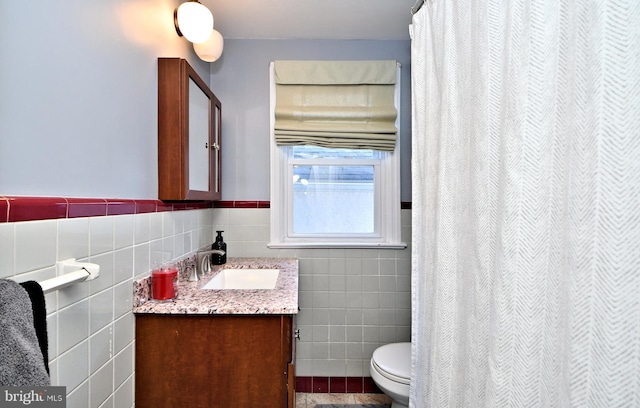 full bathroom with toilet, wainscoting, tile walls, and vanity