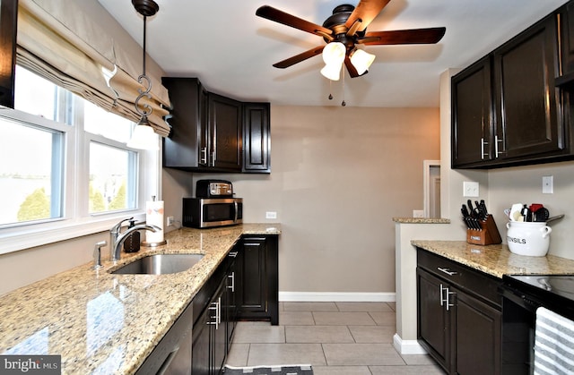 kitchen featuring light tile patterned flooring, a sink, baseboards, light stone countertops, and stainless steel microwave