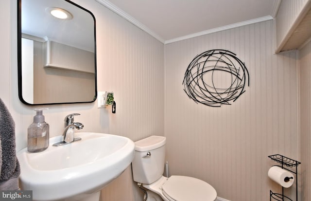 half bath featuring ornamental molding, a sink, and toilet