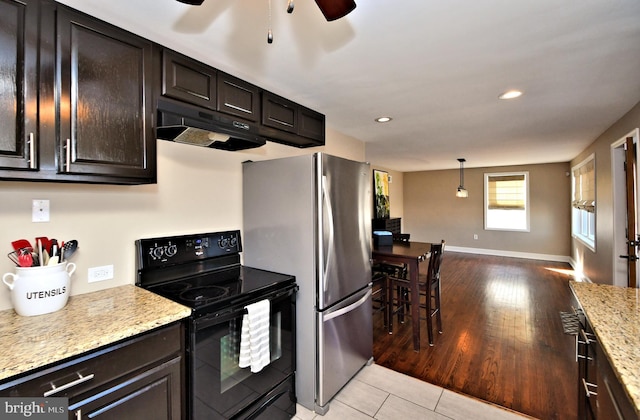 kitchen with baseboards, light wood-style floors, freestanding refrigerator, under cabinet range hood, and black range with electric cooktop