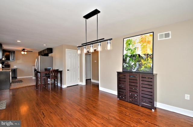 living room featuring ceiling fan, wood finished floors, visible vents, and baseboards