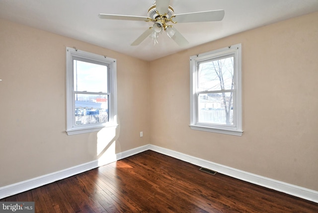 spare room featuring dark wood-style flooring, visible vents, ceiling fan, and baseboards