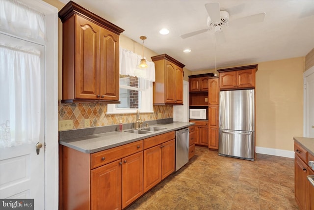 kitchen featuring a sink, hanging light fixtures, appliances with stainless steel finishes, brown cabinets, and decorative backsplash