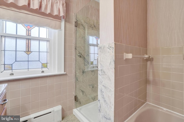 bathroom featuring plenty of natural light, a bathtub, a shower, and tile walls