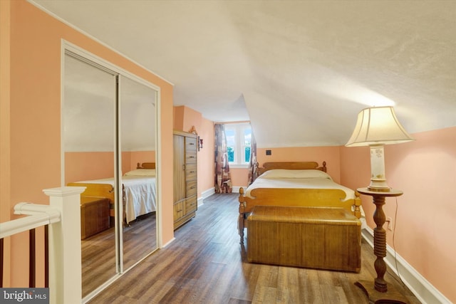 bedroom featuring a closet, baseboards, vaulted ceiling, and dark wood-style flooring