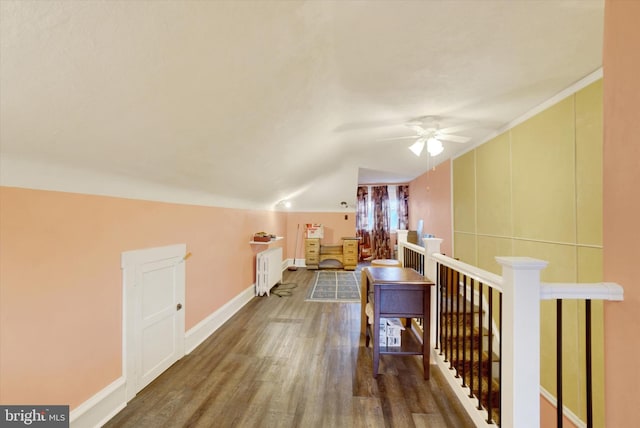 additional living space featuring baseboards, a ceiling fan, radiator, wood finished floors, and vaulted ceiling