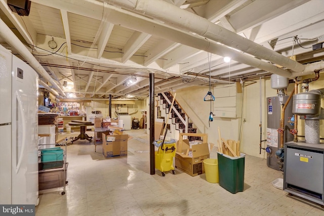 unfinished below grade area with a heating unit, stairway, tile patterned floors, freestanding refrigerator, and gas water heater