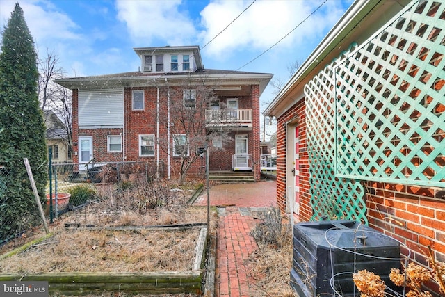 rear view of house featuring brick siding and fence