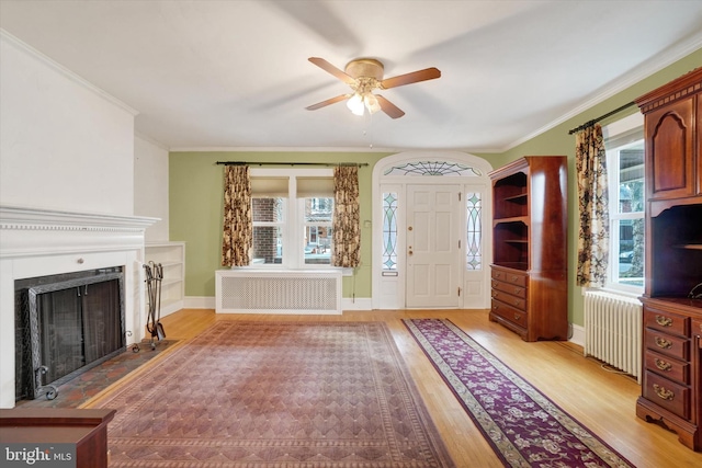 foyer entrance with ornamental molding, radiator heating unit, light wood-type flooring, and radiator