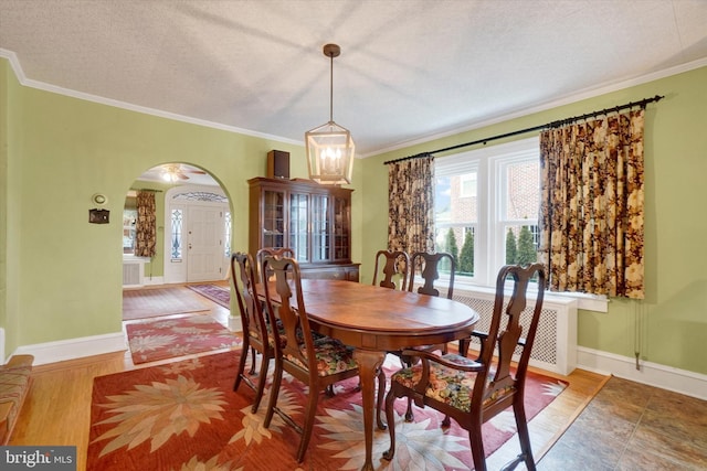 dining area featuring arched walkways, ornamental molding, a textured ceiling, and baseboards