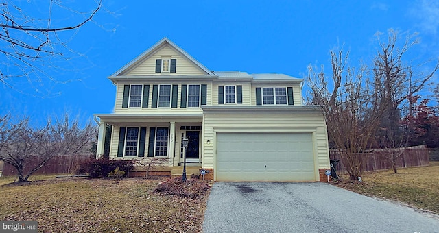 traditional-style house featuring an attached garage, fence, and aphalt driveway