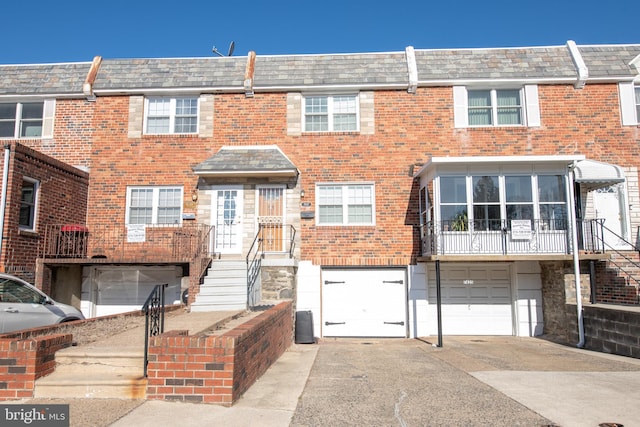 townhome / multi-family property with driveway, an attached garage, mansard roof, and brick siding