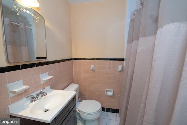 bathroom with toilet, tile walls, vanity, wainscoting, and tile patterned floors