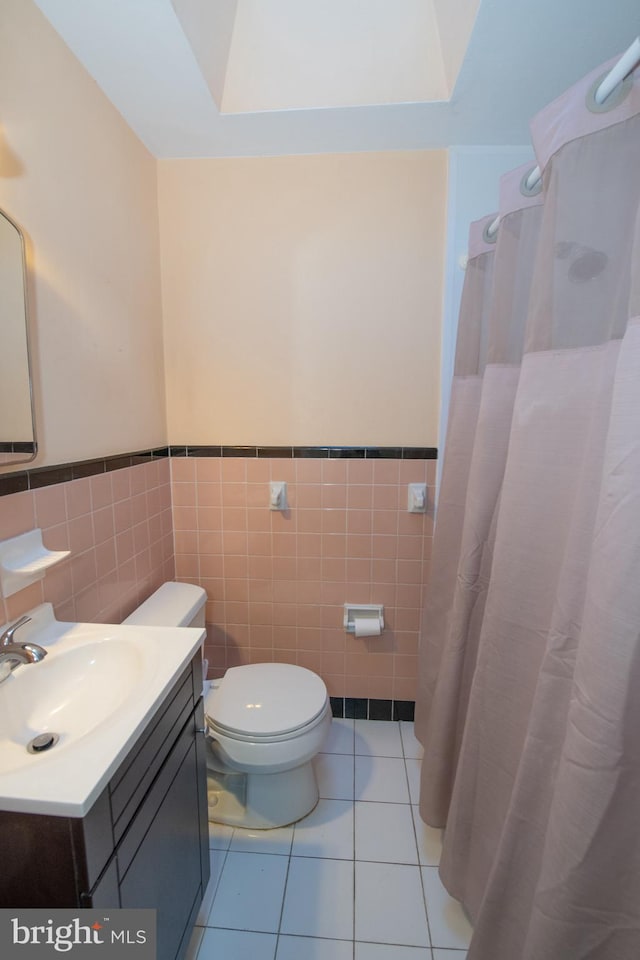 full bath featuring vanity, wainscoting, tile patterned flooring, and toilet