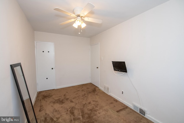 empty room with carpet, visible vents, ceiling fan, and baseboards