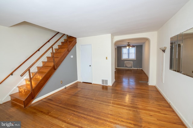 interior space featuring baseboards, visible vents, arched walkways, wood finished floors, and stairs