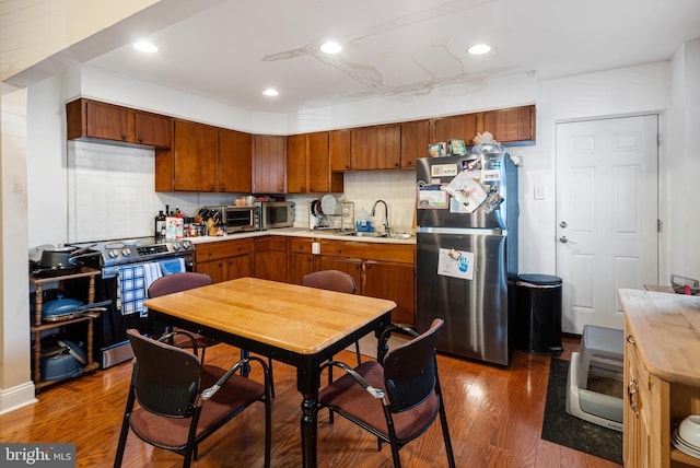 kitchen with sink, dark wood-type flooring, stainless steel appliances, and tasteful backsplash