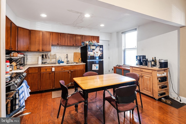 kitchen with sink, dark wood-type flooring, black fridge, and backsplash