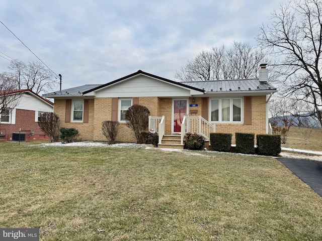 view of front of property featuring central AC, brick siding, a chimney, and a front lawn