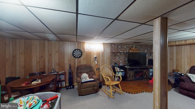 carpeted living area featuring wood walls and a paneled ceiling