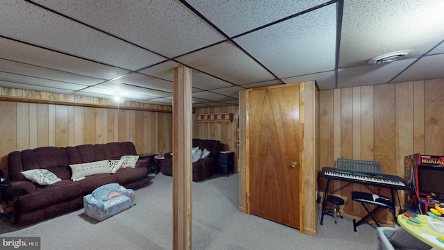 interior space featuring visible vents, a drop ceiling, and wooden walls