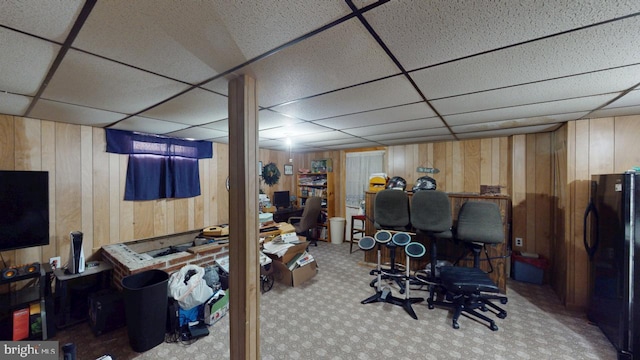 office area with carpet flooring, wood walls, and a drop ceiling