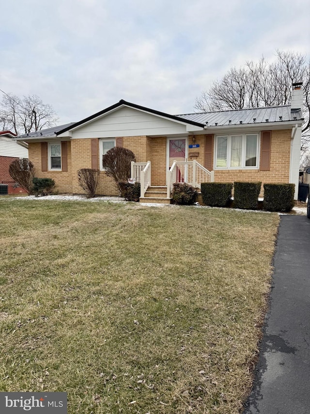 single story home with a front yard, a chimney, metal roof, and brick siding